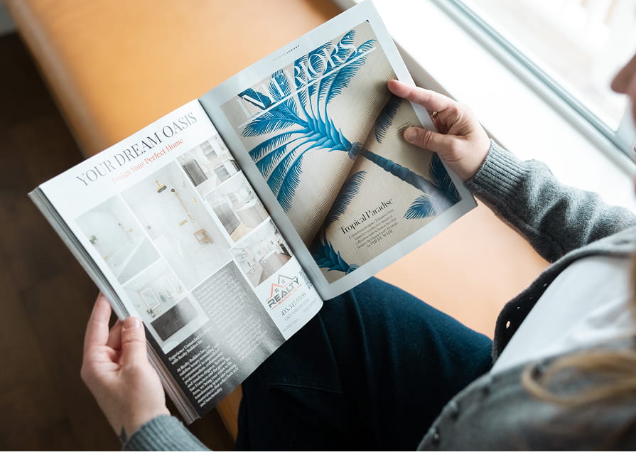 A person sitting on a couch, intently reading a magazine.