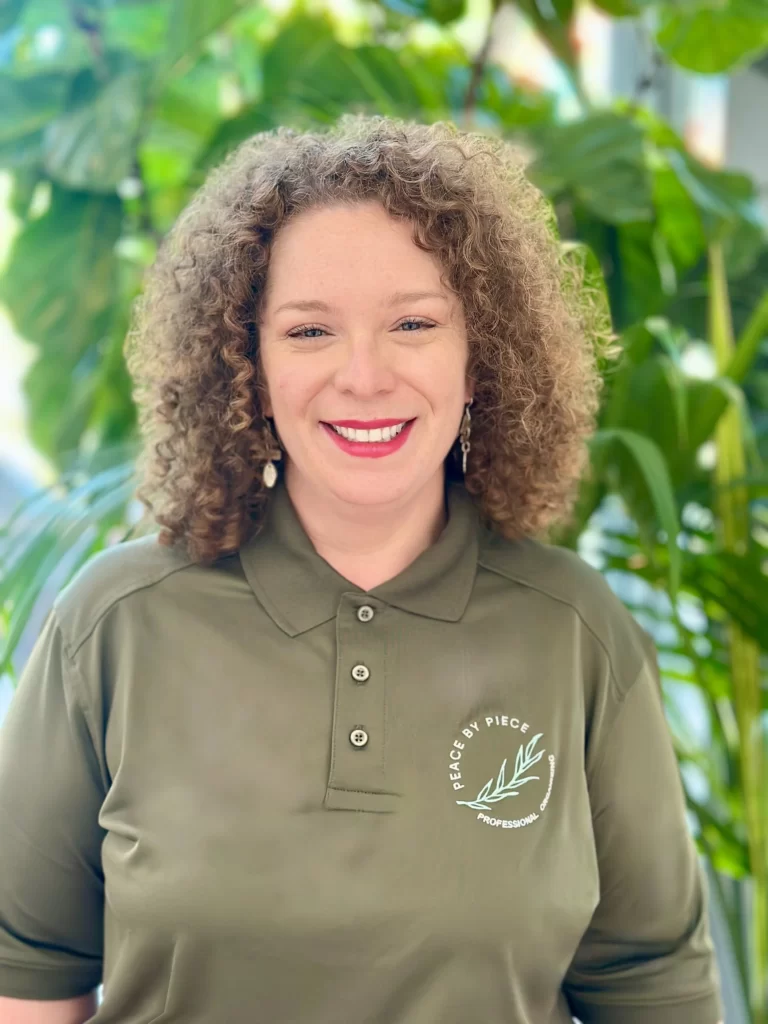 Peace by Piece organizer Naomi wearing an olive green polo shirt with the company's logo.